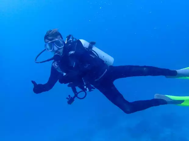 A scuba diver giving a thumbs up while swimming through the Great Barrier Reef.
