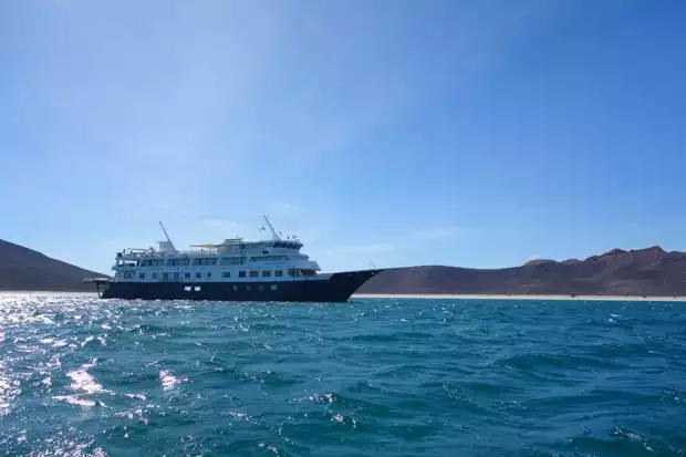 Uncruise small ship cruise anchored in the waters of Baja next to a sandy beach island.