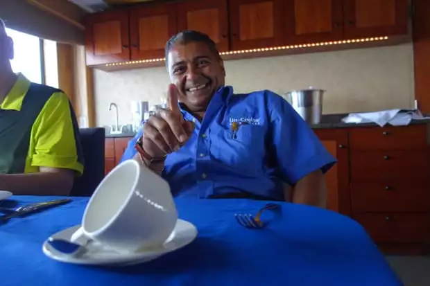 Uncruise small ship crew member relaxing at a table on the boat.