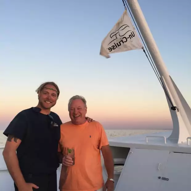 Happy Baja travelers posing in front of the Uncruise flag on the deck of the small ship cruise.