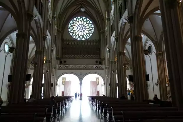 Interior of the cathedral with high vaulted ceilings, pillars and pews lining the floor of the church in Guayaquil.