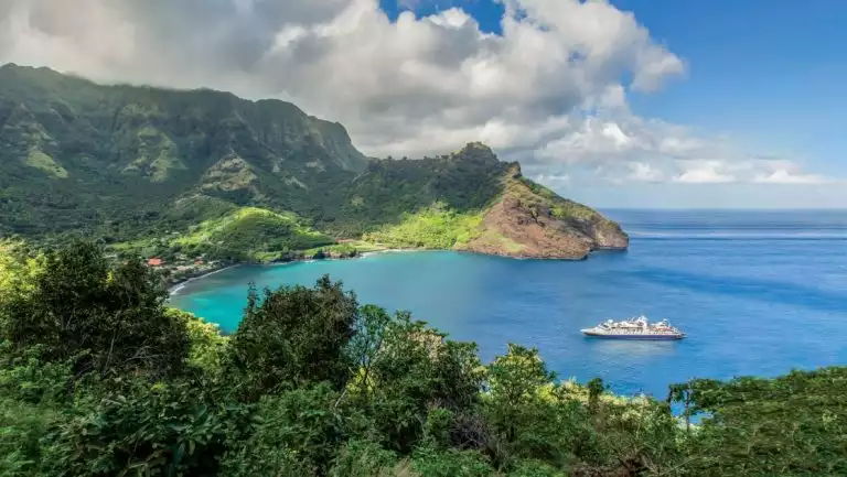 Aerial view of small ship parked in the bay of a lush green island in the Easter Island to Tahiti: Tales of the Pacific cruise.