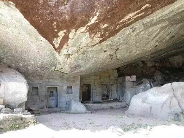 Stone house Inca ruin set underneath a rock cavern on a Machu Picchu land tour.