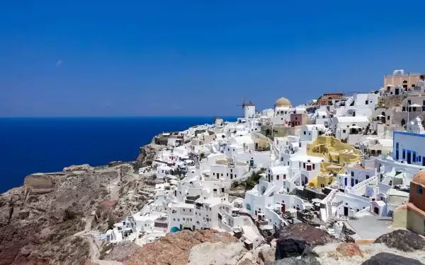 A Greece city view in the Mediterranean with white buildings and a deep blue sea.