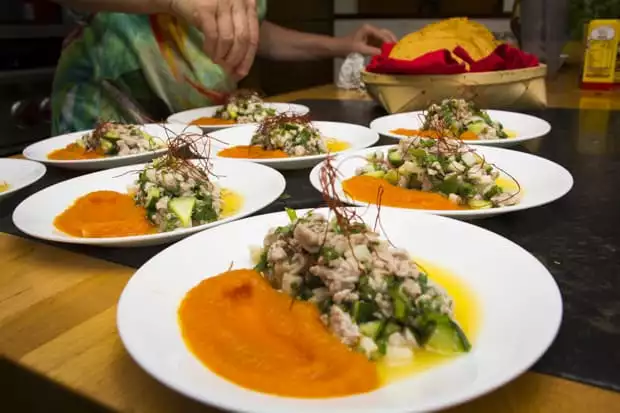 Plates of fresh ceviche and sauce on a table with the chef.