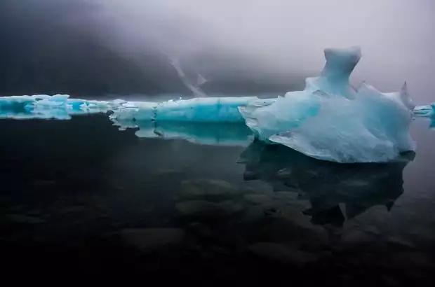 Bright blue glaciers in a dark misty bay at Kenai Fjords Alaska. 