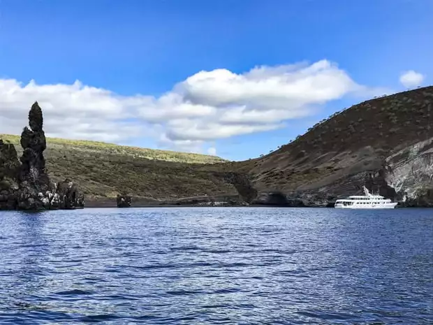 Small ship cruise WildAid's Passion anchored in a bay off the coast of a Galapagos island with rock pinnacles.