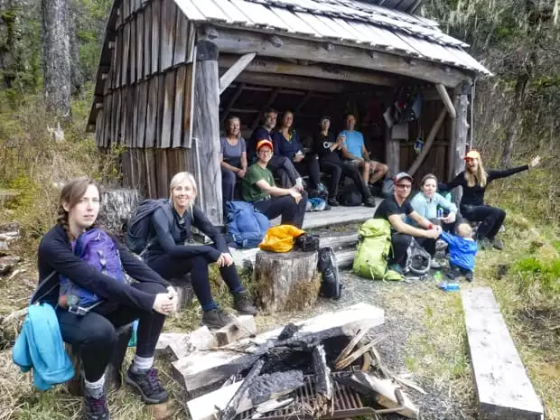 Guests from a small ship cruise sit with their guides to rest while on a Three Lakes Hike in Alaska. 
