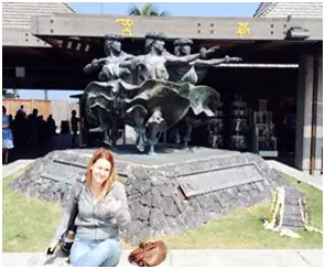 Woman sitting in front of a statue of Hawaiian dancers