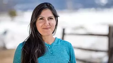 adventuresmith explorations adventure specialist leslie camacho wearing a turquoise shirt smiling on a sunny day with snow in the background