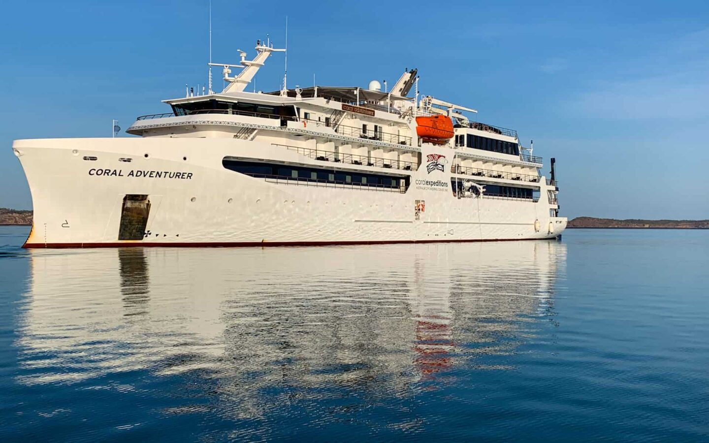Small yacht coral adventurer floats in Australian a bright blue ocean underneath a bright blue sky with no clouds