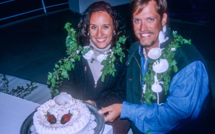 A newlywed couple cut their cake on while outside in the dark on a small ship cruise