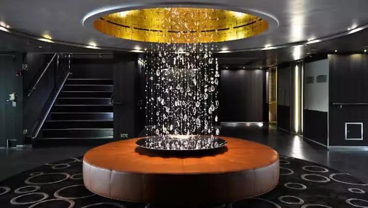 Lounge with circular red bench, crystals on wire & dark panelling aboard L'Austral expedition ship.