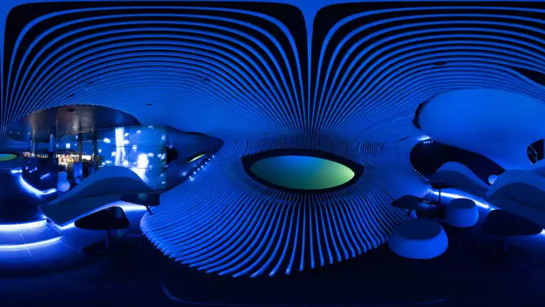Blue Eye lounge aboard Le Champlain french luxury ship, located in the ship's hull, with 2 large oval portholes, many small couches & blue gill-like walls.