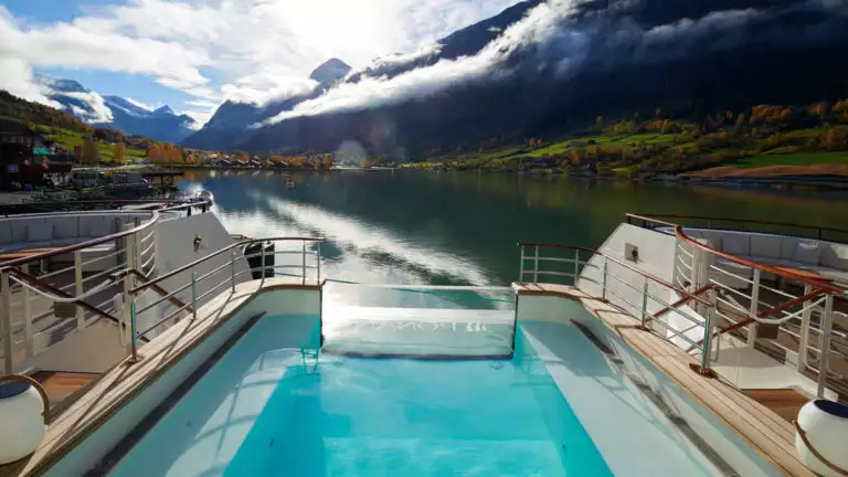 View from aft infinity pool surrounded by chaise loungers, aboard Le Laperouse French small ship.
