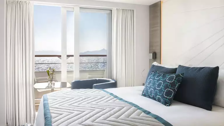 Grand Deluxe Suite aboard chic expedition ship Le Lyrial, with king bed, nautical decor & private balcony.