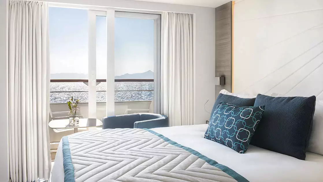 Grand Deluxe Suite aboard chic expedition ship Le Lyrial, with king bed, nautical decor & private balcony.