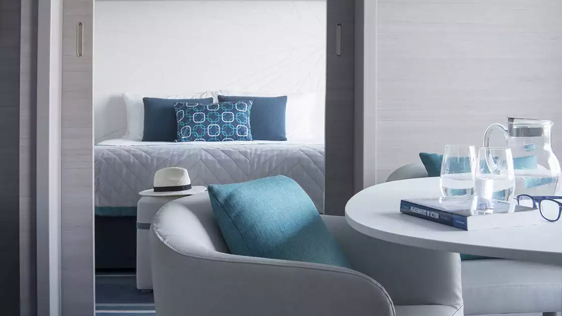 Prestige Suite on Le Lyrial French small ship, with table & armchair in foreground & king bed in separate room in the background.
