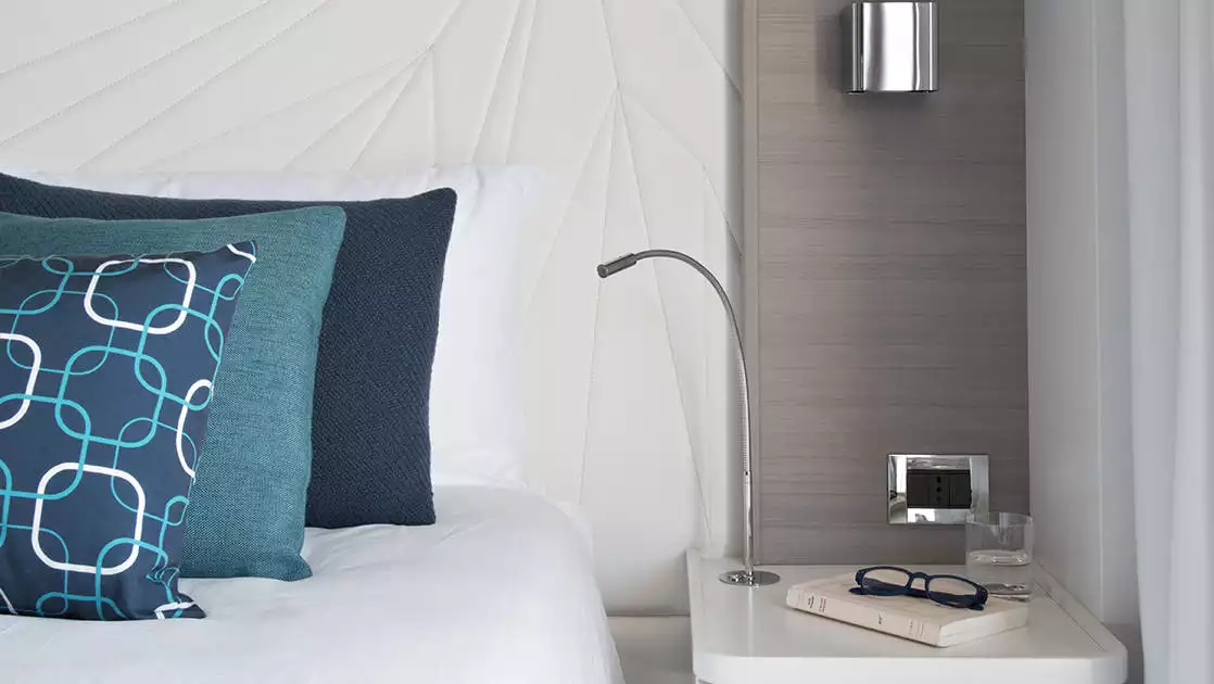 Superior Stateroom aboard Le Lyrial French luxury ship, with bed, bedside table, reading light, lamp & blue-&-white decor.