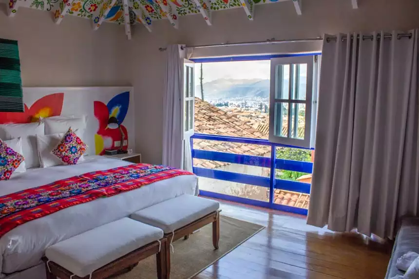 Inside of a room at the El Retablo in Cusco, Peru. Bright white decor with pops of bright colored wall art and ceiling.
