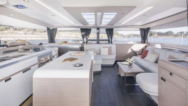Interior of Belize small ship catamaran with a modern light design featuring a kitchen, sitting area and large windows.