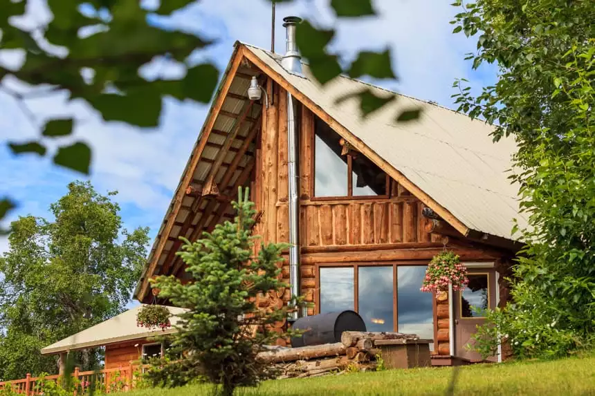 The main building of Winterlake Lodge , and a frame log cabin surruonded by trees