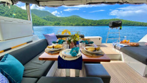 Al fresco aft dining area on Ventana al Mar catamaran in Belize set for a meal with cushioned bench seating, tropical colors.