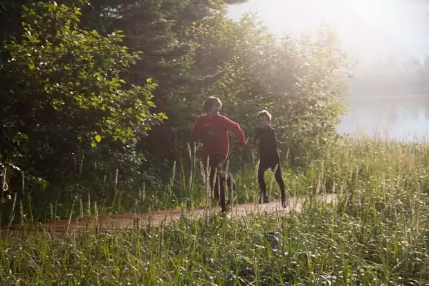 Two kids racing along a path in Alaska having fun while on a land tour.
