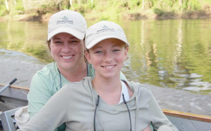 Mother and daughter on a skiff in the jungle smiling while on a family vacation.