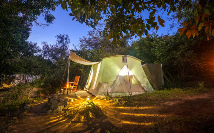 Exterior of Baja glamping tent lit up by lanterns at night.