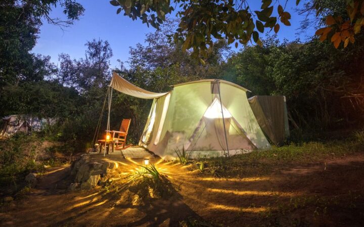 Exterior of Baja glamping tent lit up by lanterns at night.