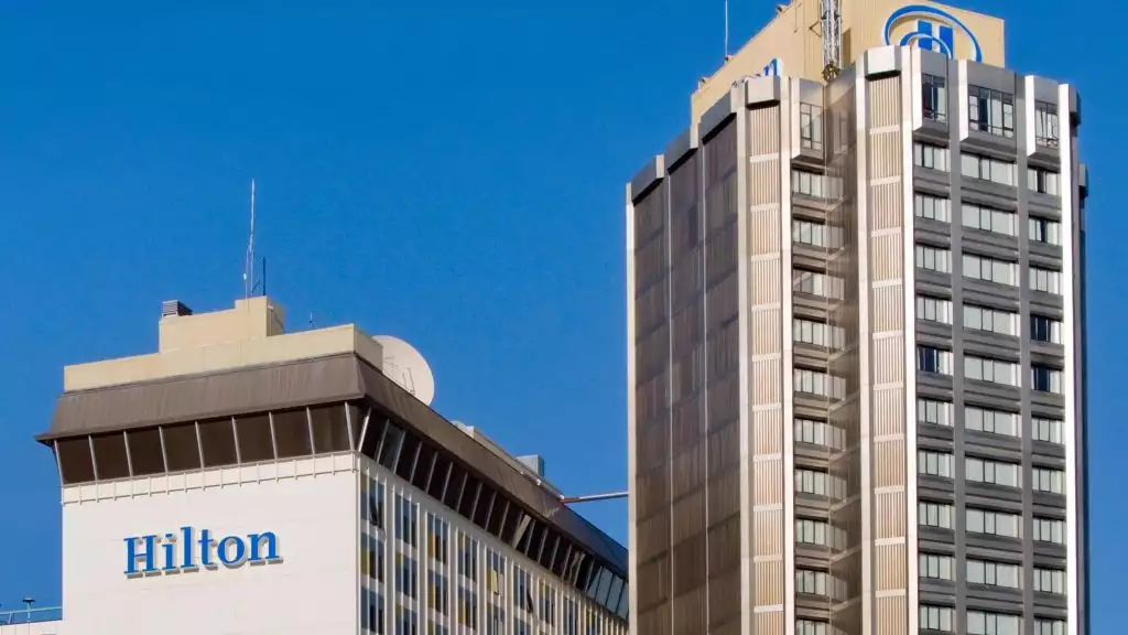 The exterior of the Hilton Downtown Anchorage hotel, blue sunny day, with a tall 600 room building.