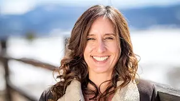 adventuresmith explorations chief financial officer lisa exley smith smiles on a sunny day with mountains behind her