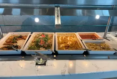 Food buffet selection aboard Greg Mortimer ship, white large serving plates set next to each other hold colorful menu items.
