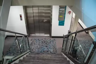 From the top of a set of stairs looking down at the metal doors of the Greg Mortimer's on board elevator.