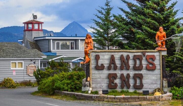 Entrance sign to Land's End Resort in Homer, Alaska, with nautical themed architecture & figurines set amongst mountains.