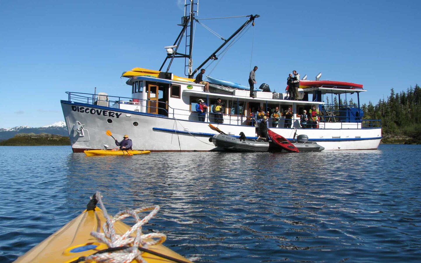 alaska small ship anchored in calm water on a sunny day with a kayak bow in the foreground