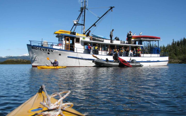 alaska small ship anchored in calm water on a sunny day with a kayak bow in the foreground