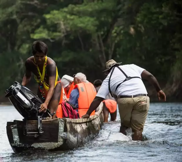 costa rica travelers arriving with 2 men guiding the canoe.