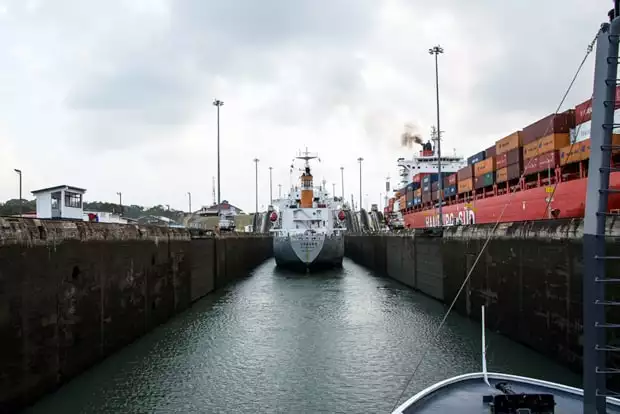 Small ship cruise in the locks of the Panama Canal with a another vessel and cargo ship in the locks.