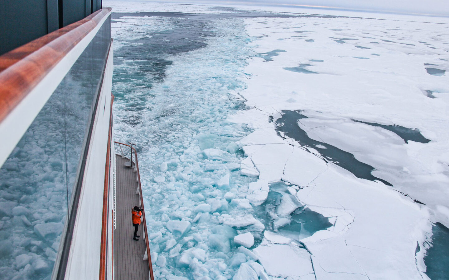 A photographer alone on a North Pole cruise ship deck takes photos of endless ice