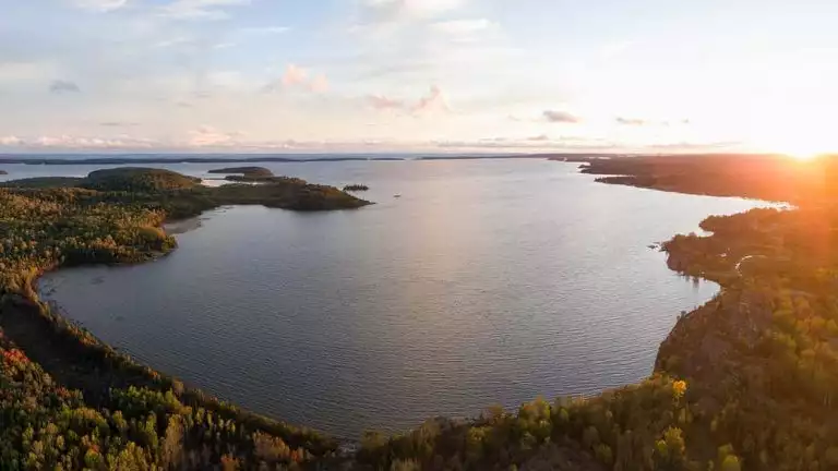 Aerial view of a calm inlet on Lake Huron at dusk with fall colors under clouds, seen on small ship great lakes cruises.
