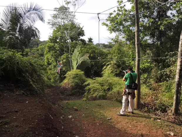 Photographer taking a picture of a travelers zip lining through the rain forest.