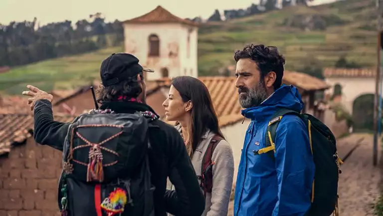 Explora Peru Sacred Valley travelers stand in a mountainside town listening to a guide explain their surroundings.