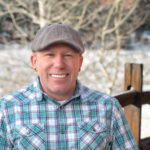 Portrait of Kiel Sprague in a plaid shirt with snowy background and a fence