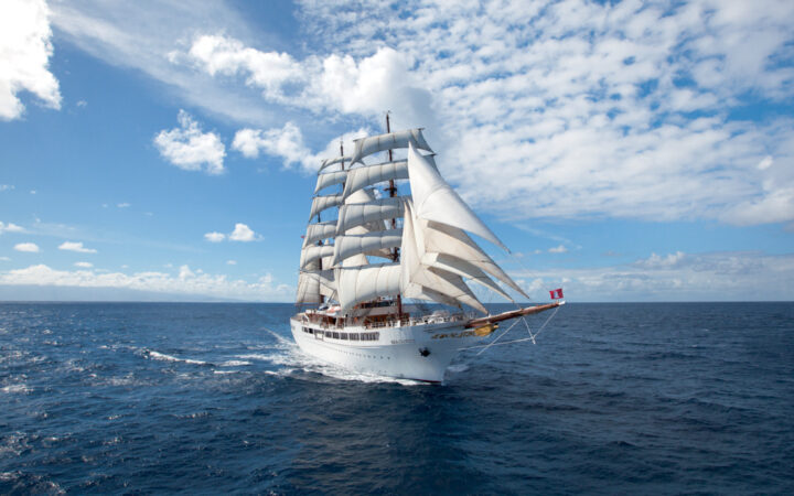 Sea Cloud II: Lindblad 3-masted barque tall ship with white exterior sails in open waters on a partly cloudy day.