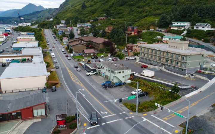Aerial view of Kodiak Compass Suites hotel in Alaska on a cloudy day, 1 block off the water & backed by tall green mountains.