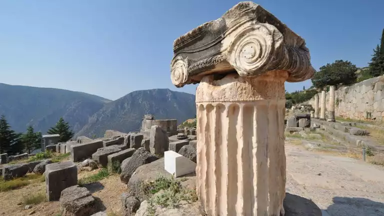 Tan ancient Grecian column sits near other ruins on a hilltop in the sunshine on a Le Ponant Cyclades small ship cruise.