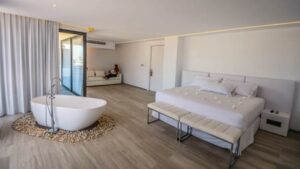 Suite interior with bed, couch, bench & large tub in middle of room at Golden Bay Galapagos hotel on San Cristobal in the Galapagos Islands.