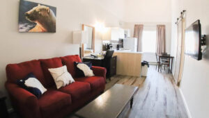 Suite with small kitchen, desk and chair, red couch, coffee table, TV and polar motif at the Polar Inn in Churchill, Canada.
